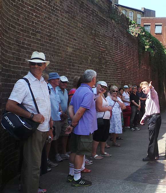 Richard guiding a Dickens tour and standing alongside the wall of the Marshalsea Prison.